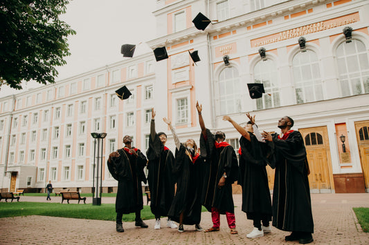 Group of graduates throwing their caps in the air outside of a school building